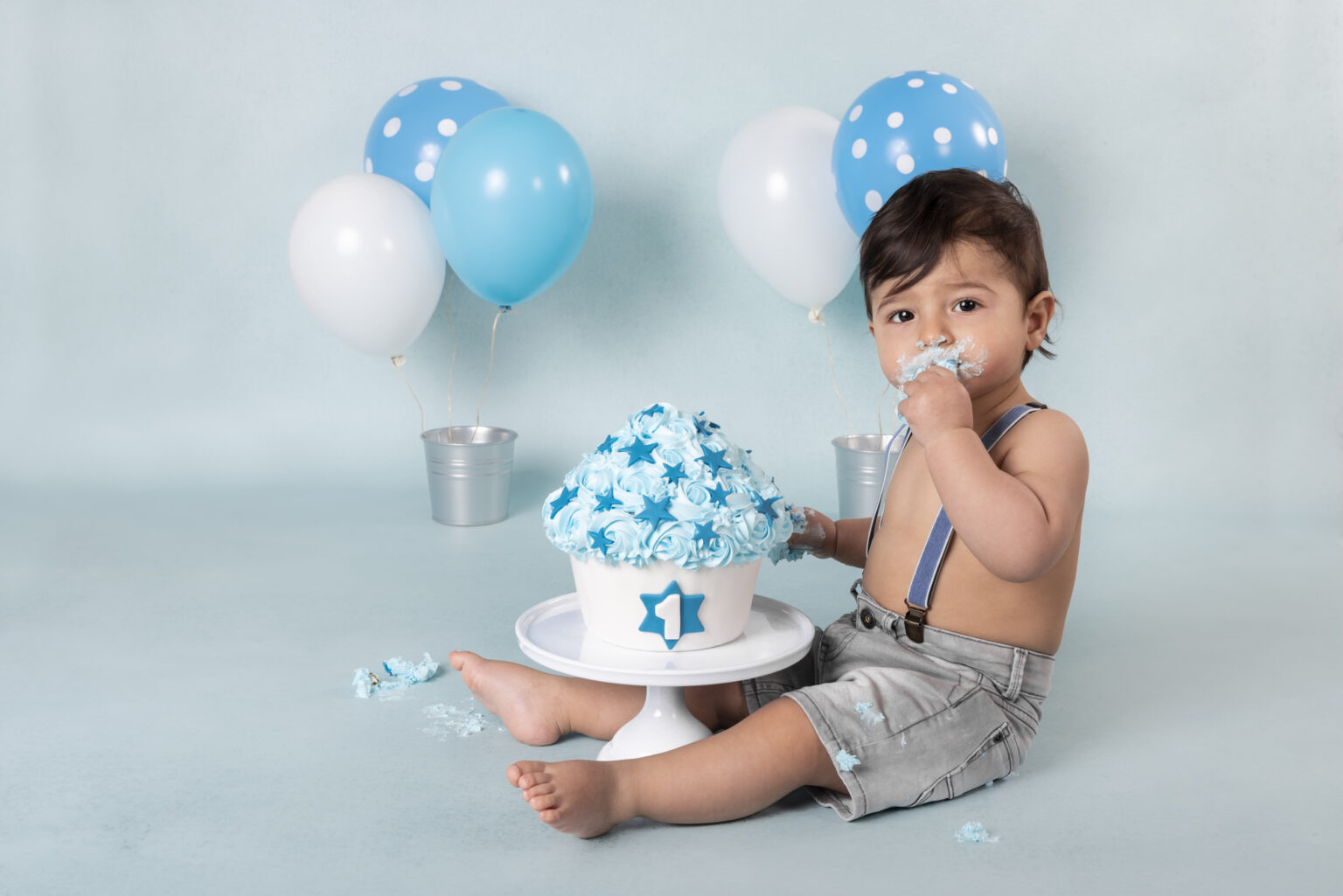 Jongetje bij een blauwe cakesmash taart met sterren en blauwe ballonnen