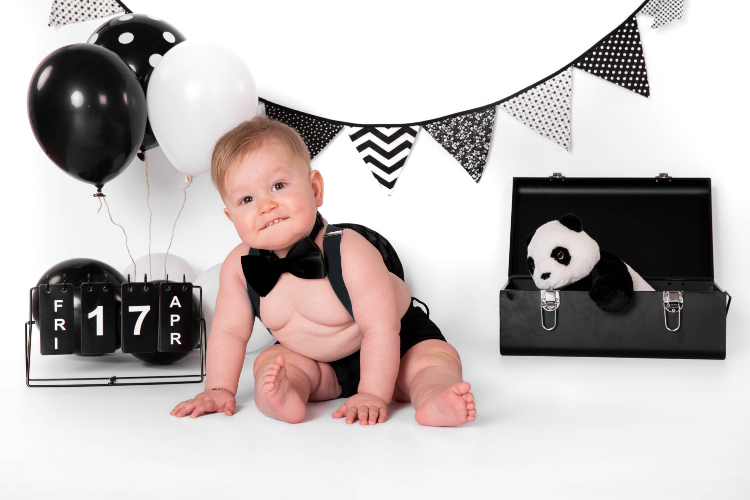 Kruipende baby van 1 jaar tussen zwarte en witte ballonnen