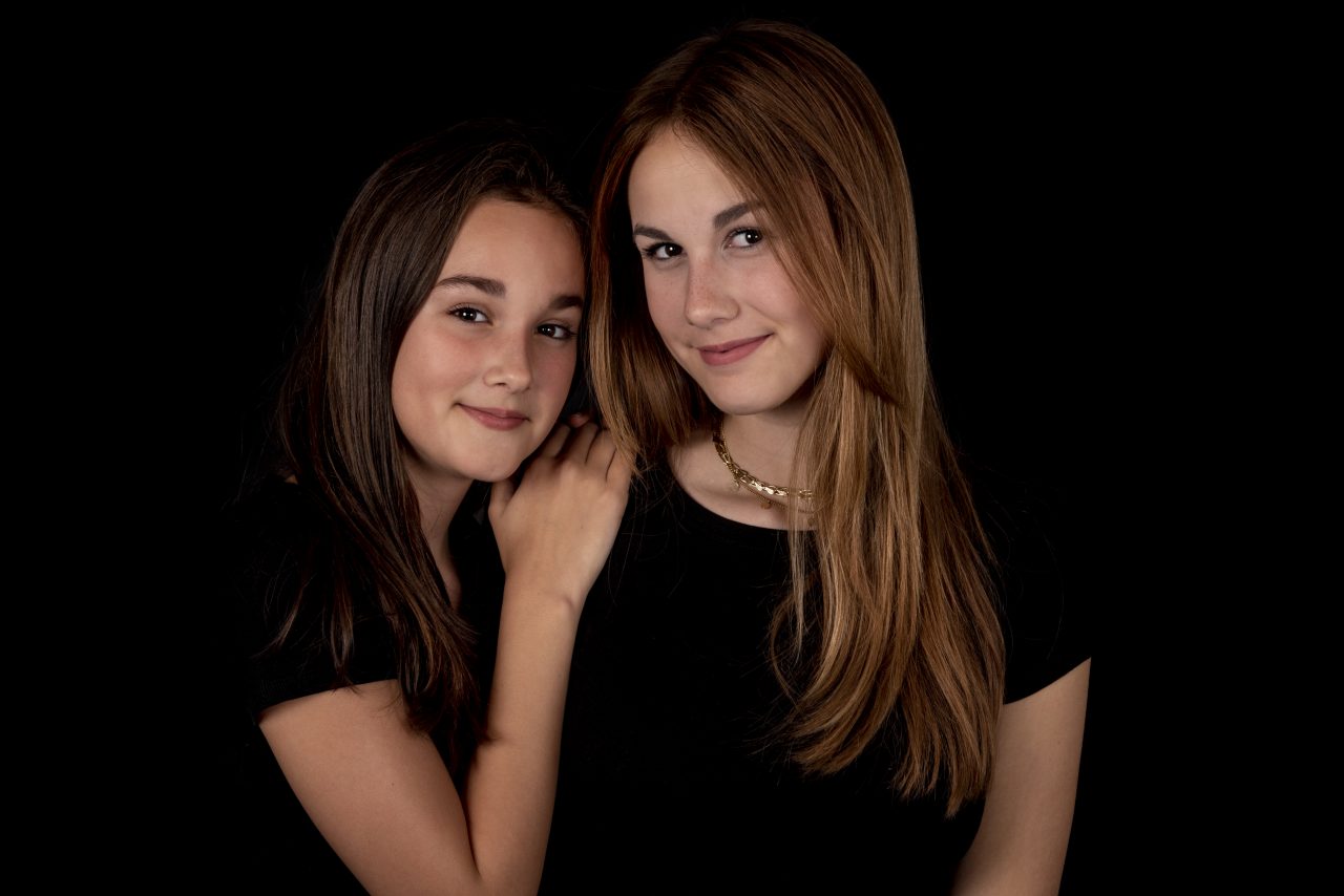 Twee meisjes samen op de foto tegen een donkere achtergrond in de studio
