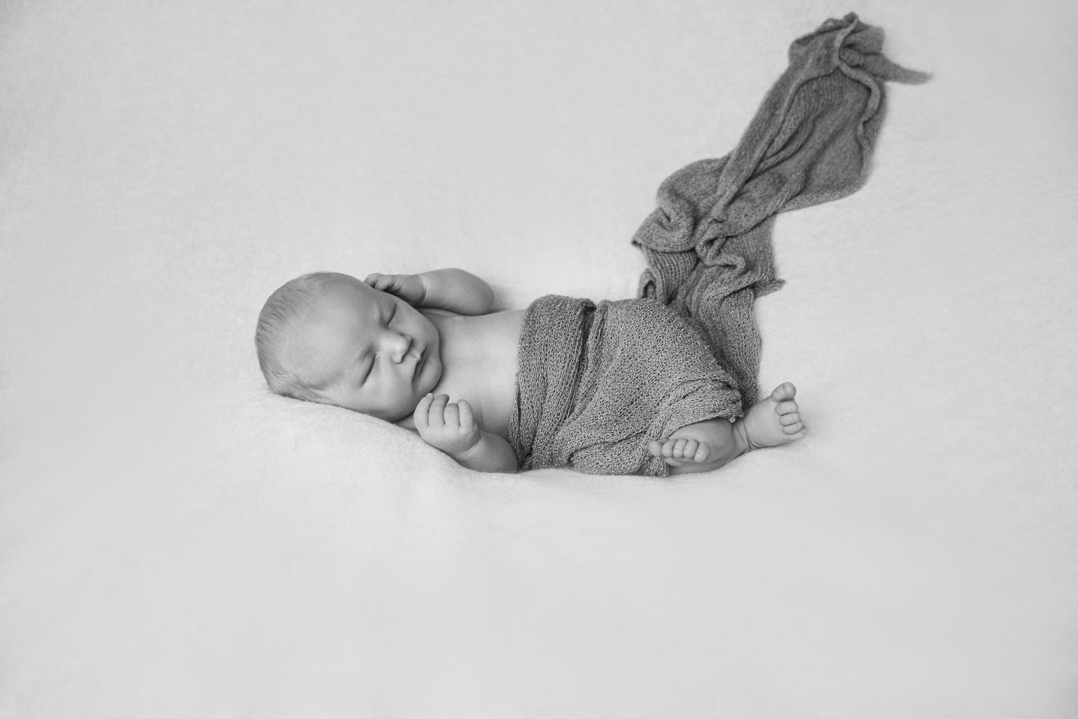 Pasgeboren baby op zijn buik in een gebreid pakje, in zwart-wit