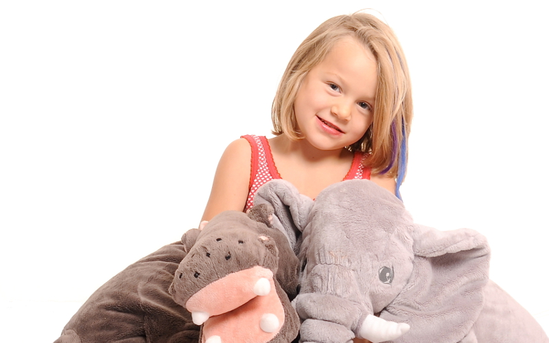 Meisje met een grijze knuffelolifant op een witte achtergrond