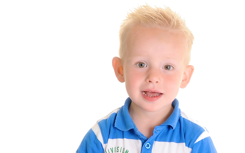 Jongen in een blauw poloshirt lacht op een witte achtergrond