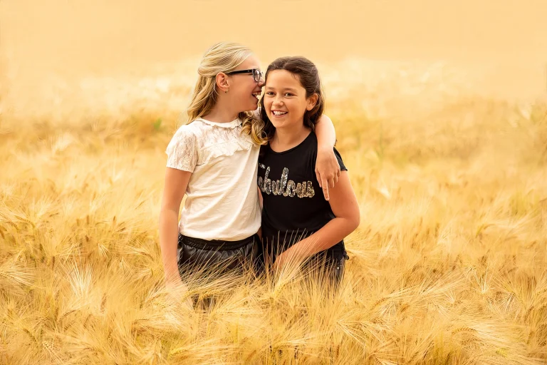 Kinderen lachend in een graanveld tijdens een ontspannen kindershoot door 22 Eendjes Kinderfotografie in Midden-Nederland