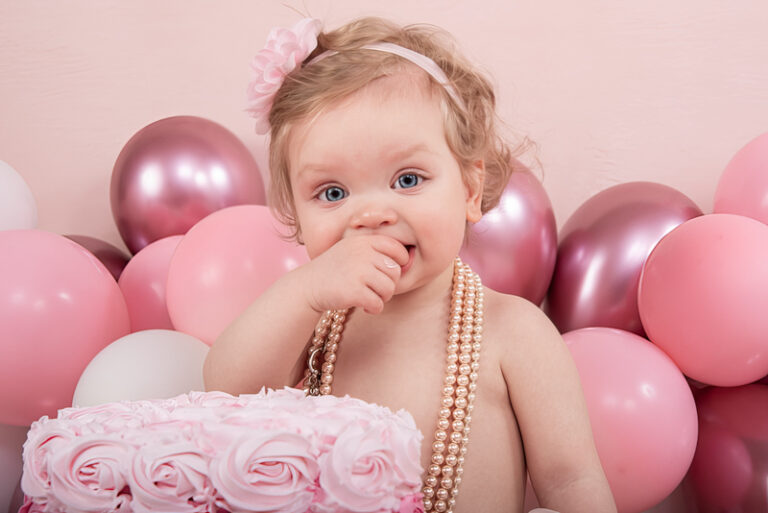 Kind van een jaar met taart en ballonnen tijdens een cakesmash fotoshoot