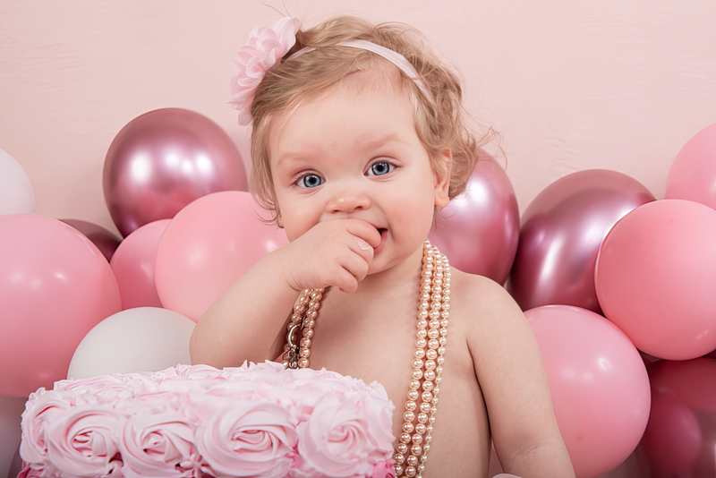 Kind van een jaar met taart en ballonnen tijdens een cakesmash fotoshoot