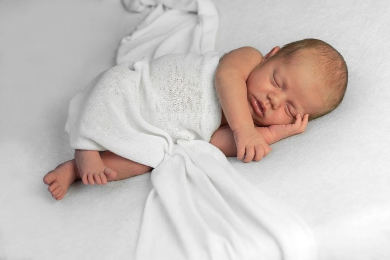 Pasgeboren baby ingebakerd in het wit tijdens een newborn shoot in Culemborg