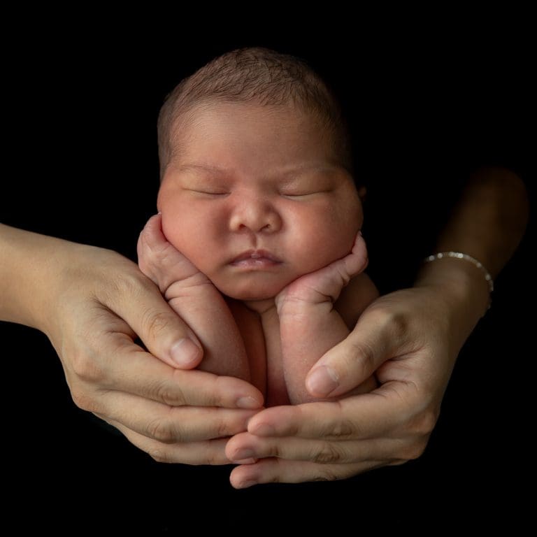 Gezichtje van een pasgeboren baby in de handen van zijn ouders