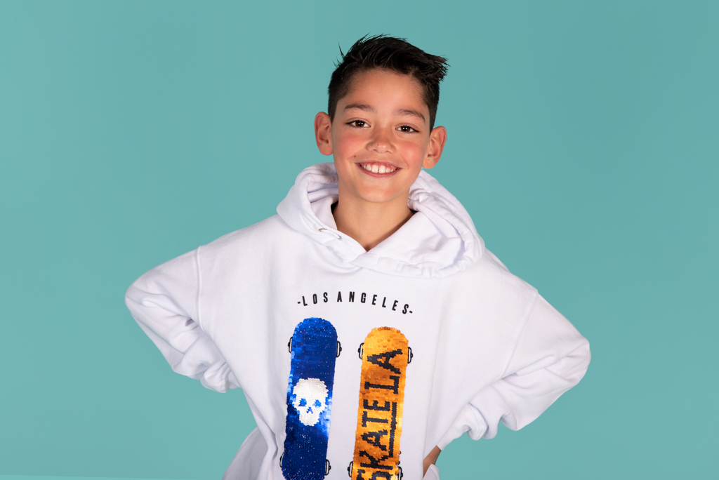 Tiener in een witte hoodie tegen een turquoise achtergrond in de studio