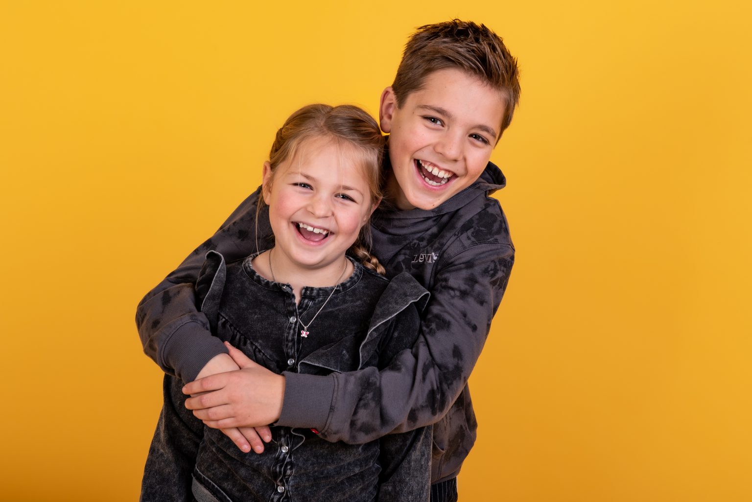 Broer en zus knuffelen tijdens een kinderfotoshoot in de studio