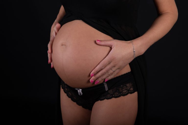 Zwangere vrouw tijdens een zwangerschapsshoot in de studio