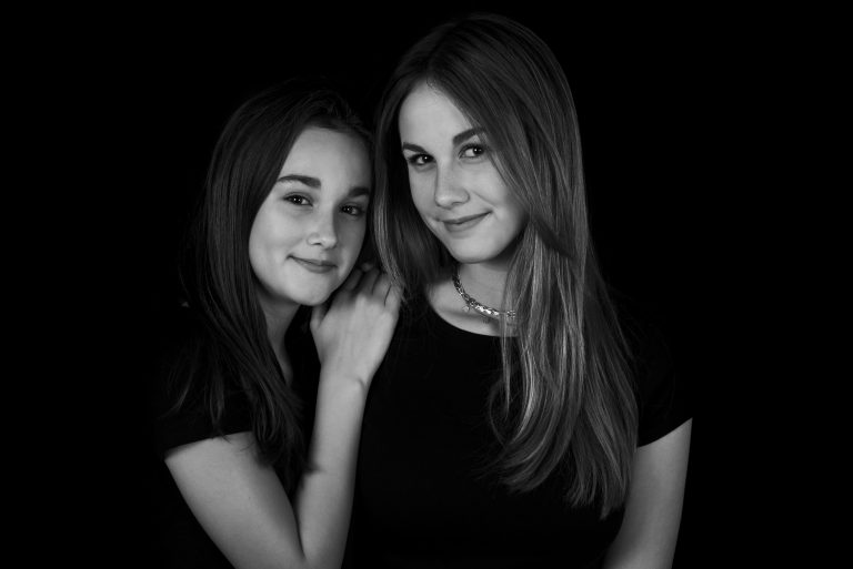 Twee modellen samen tijdens een portfolioshoot op een zwarte achtergrond