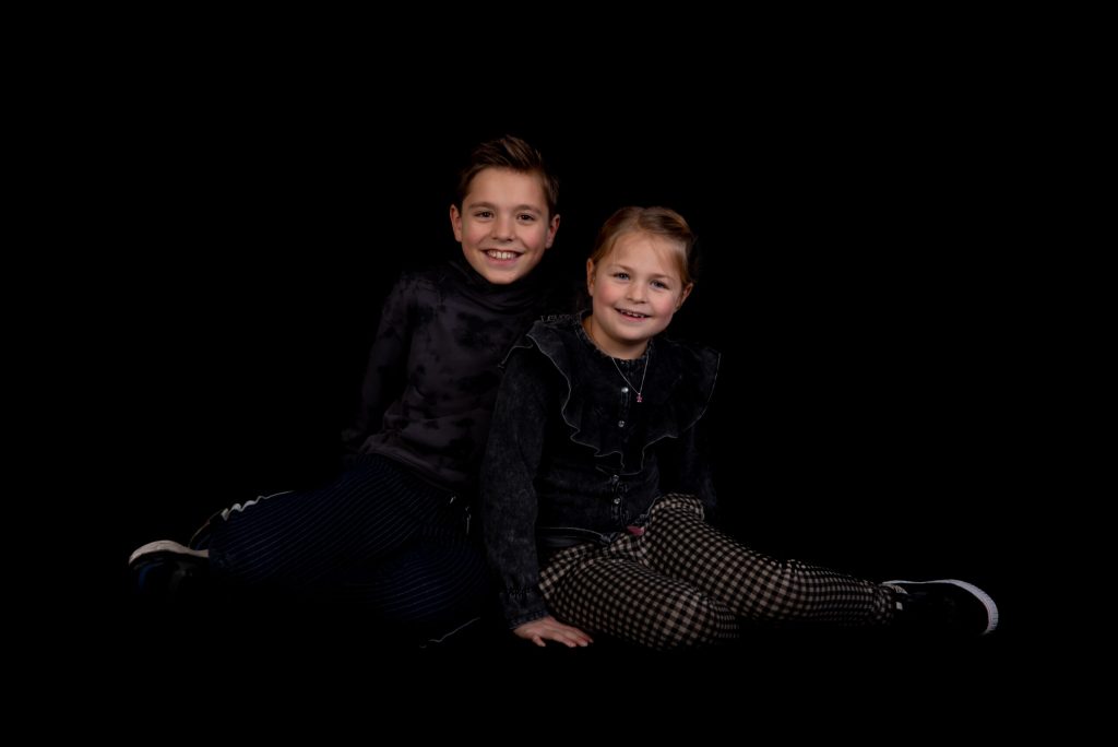 Broer en zus zitten samen op een zwarte achtergrond in de studio