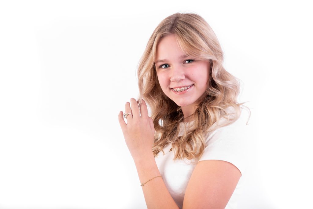 Tienermeisje met lang blond haar tegen een lichte achtergrond