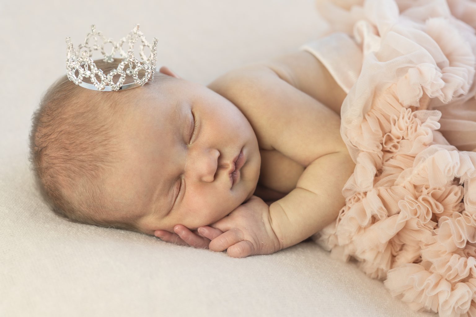 Pasgeboren baby met een kroontje op een perzikkleurige stof