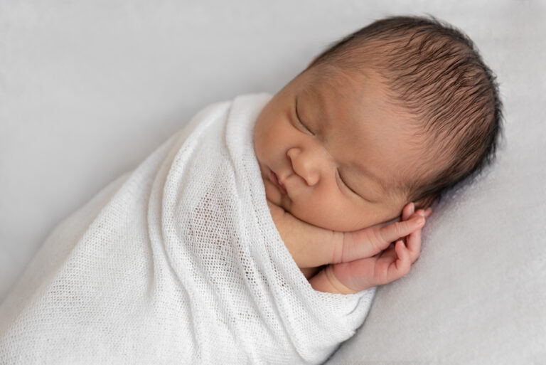 Pasgeboren baby ingebakerd in het wit, geschikt voor een geboortekaartje