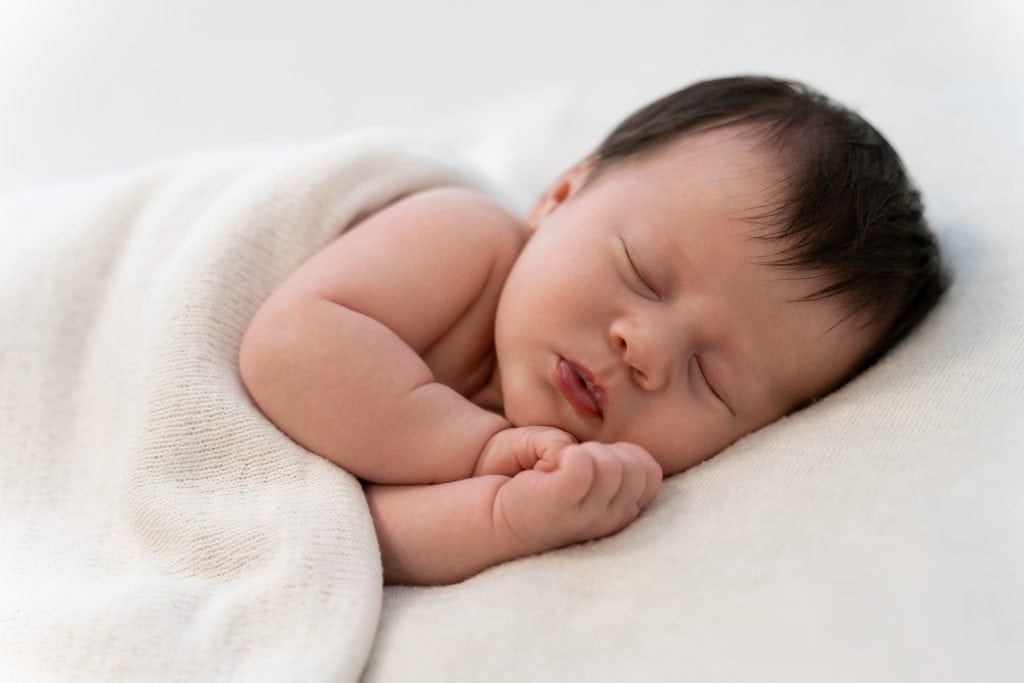 Pasgeboren baby slaapt ingebakerd tijdens een newborn shoot bij 22 Eendjes