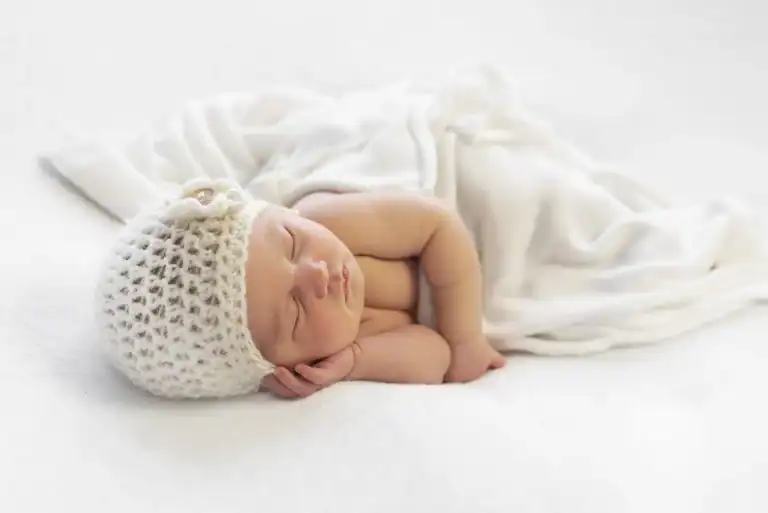 Pasgeboren baby met gehaakt mutsje slaapt tijdens een newborn shoot bij het gezin thuis