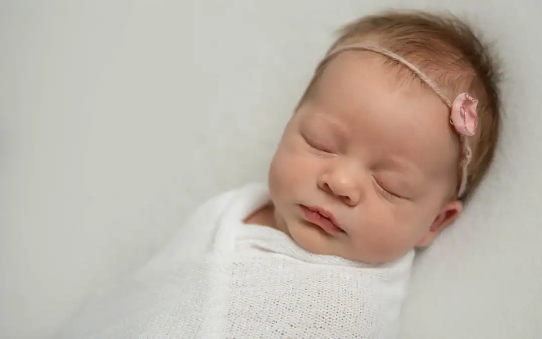 Pasgeboren baby slaapt ingebakerd tijdens een newborn shoot in Culemborg