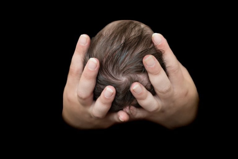 Handen van de ouders om het hoofdje van hun pasgeboren baby in de studio