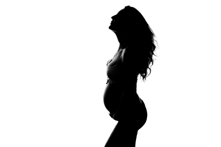 Silhouet van een zwangere vrouw in zijaanzicht tegen een witte achtergrond